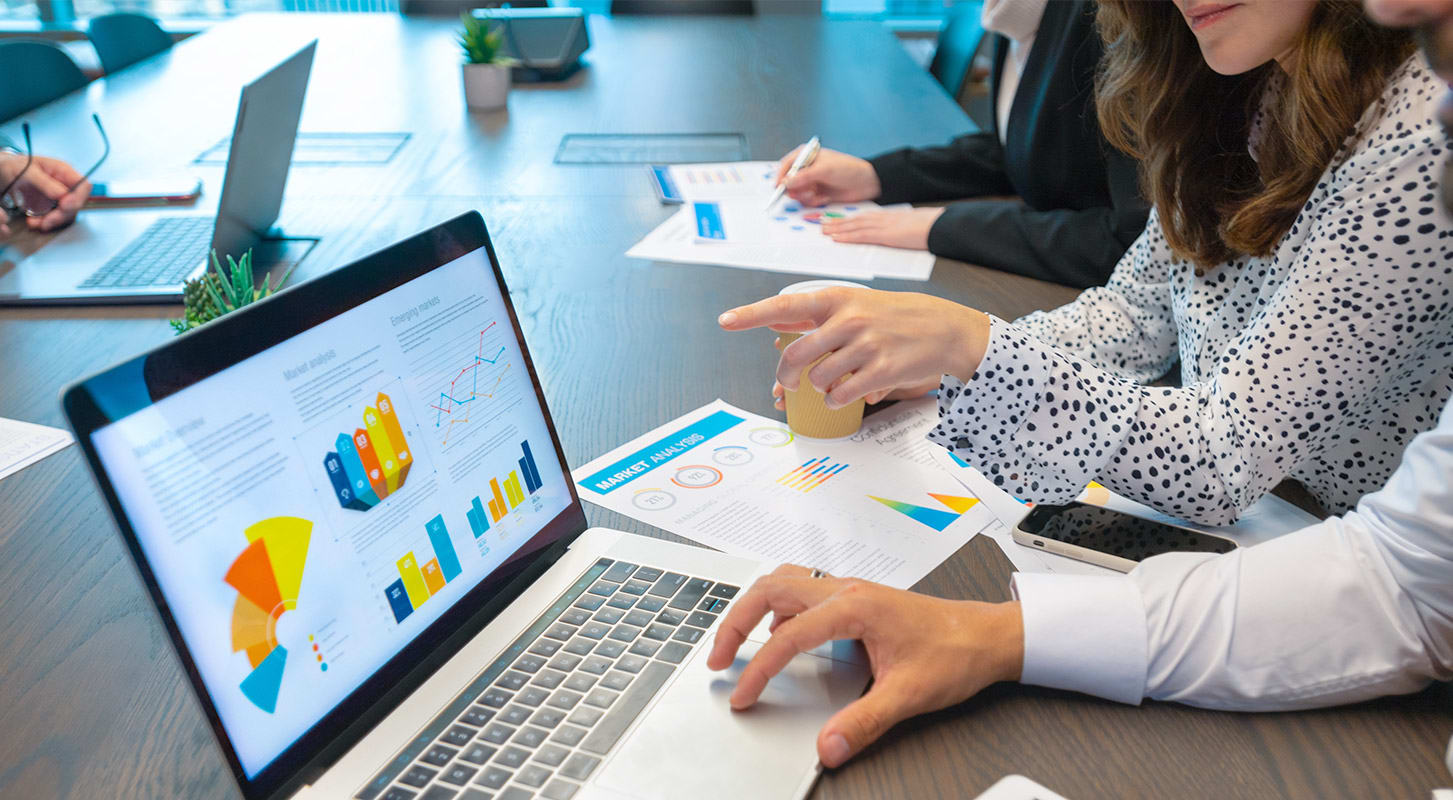 Group of business professionals collaborating on a laptop during a meeting, focused on data analytics and insights.